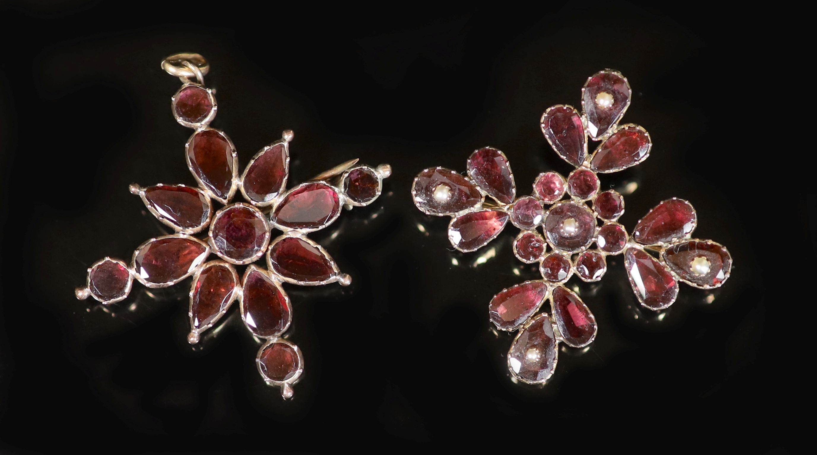 An early 19th century gold and garnet set quatrefoil pendant brooch, 44mm and one other similar brooch set with garnets and seed pearls, 42mm.